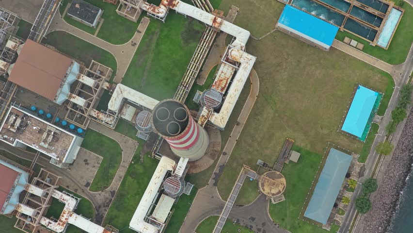 High aerial view of a coal fired power plant showing its chimney, industrial buildings, and infrastructure generating electricity