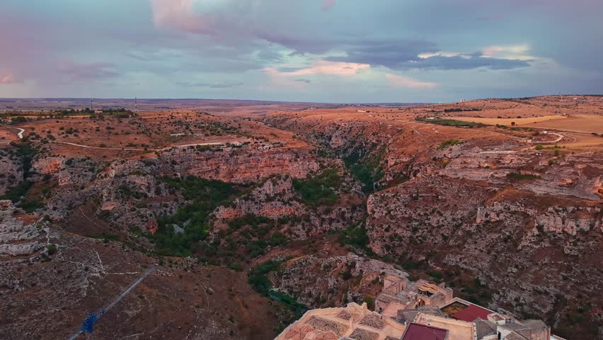 Drone view of Matera at sunset, Basilicata, Italy. The golden hour light illuminates the Cathedral of Maria Santissima of the Bruna and the historic Sassi dwellings across the ancient skyline of.