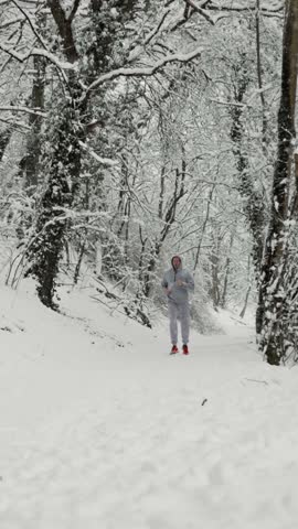 Man Swiftly Runs Through Winter Woods. Runner Speeds Along Icy Forest Trail In Vivid Footwear. Athlete Quickly Moves Through Frostbitten Forest Terrain Wearing Striking Red Running Shoes