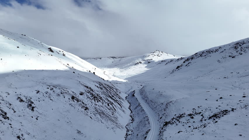 Snow Covered Mountain Road Through Winter Valley Aerial View