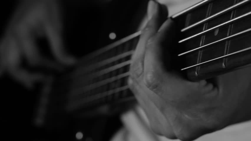 Close up of musician playing electric bass guitar in black and white.