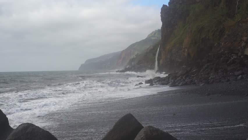 Stormy ocean waves crashing on pebble beach.