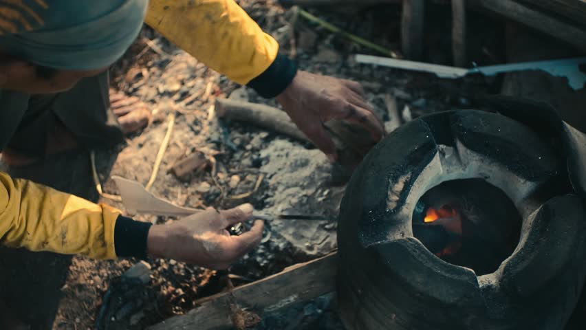 A Person Tending Small Fire Inside Recycled Tire Used as Outdoor Cook Stove Element