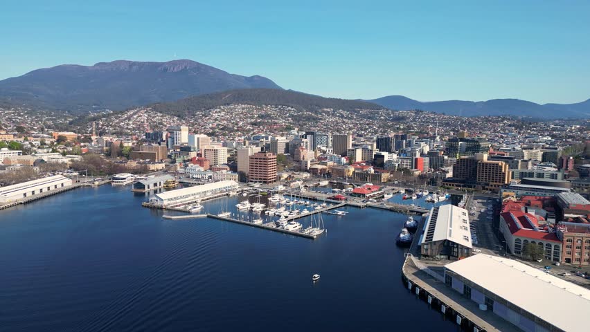 Hobart, Australia: Aerial drone footage of the Hobart central business district and Wharf harbor in Tasmania main city on a sunny day. Shot with a downward motion. 