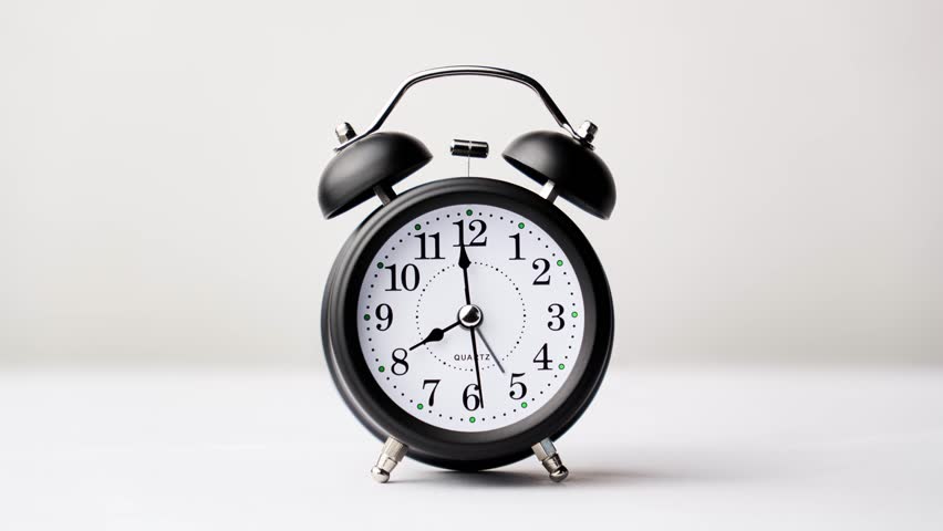 Timelapse of black and white vintage alarm clock on white background. Old fashioned alarm clock with bells. Time moving fast. Time concept. 4K, UHD