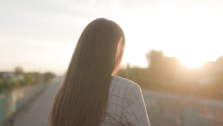 Captivating close-up portrait of a beautiful brunette woman outdoors at sunset, her face glowing with warmth and beauty.