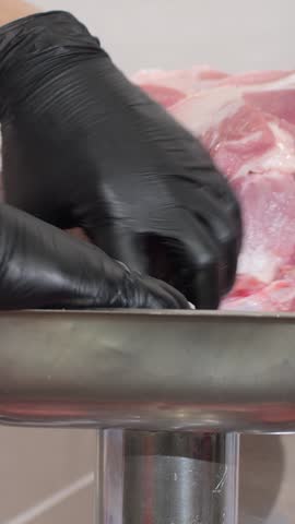 Vertical. Specialist places large pieces of meat into compartment for grinding