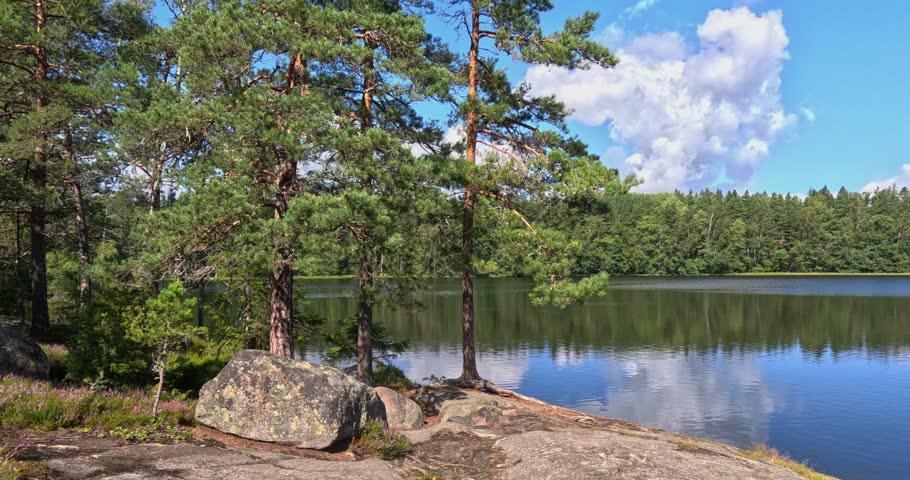 Serene Pentalanjärvi lake scene with calm lake and rugged landscape of rocky outcrops and dense forests in summer with clouds in the sky, Pentala, Espoo, Finland, Europe.