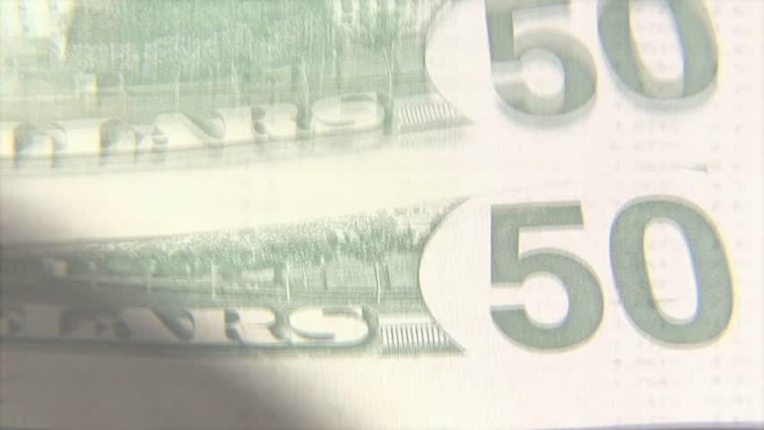 Camera shifting over 50 bill stack, jagged graph rising and falling, numeric tags showing trends. Currency, banknotes, macro, closeup, overlay, chart, data