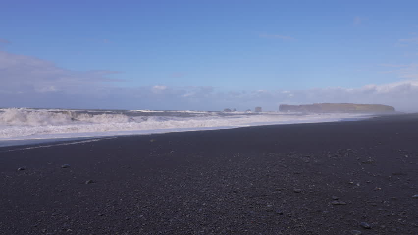 Waves crash on black sand at Reynisfjara Beach near Dyrholaey in Iceland