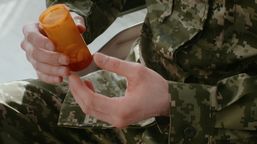 Soldier With Camo Uniform Holding Medicine Bottle While Preparing for Dosage