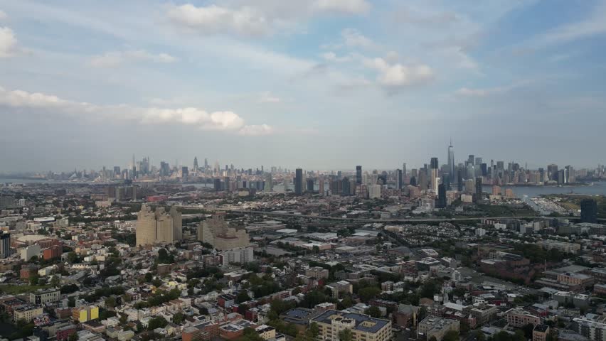 Expansive aerial view from jersey city showing the residential and industrial areas in the foreground with the iconic manhattan skyline, including the world trade center, in the distance