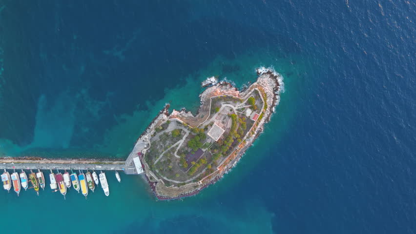 Kusadasi, Turkey. Detailed view of Pigeon Islands architecture. Shot of the central tower with whale skeleton, park aviaries, and well-preserved fortress walls. Aerial View, HEAD OVER SHOT with rotation