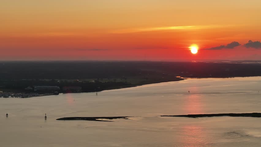 Aerial view of orange sun rising above the horizon over water in Charleston, South Carolina lowcountry landscapes during morning sunrise