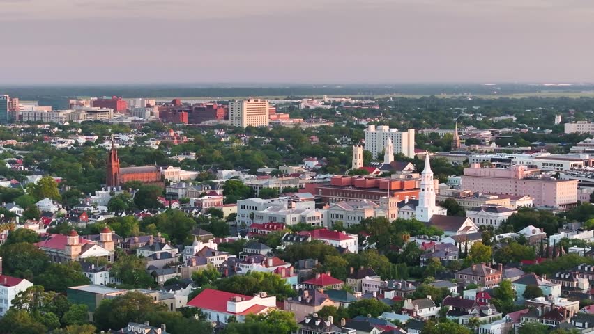 Panoramic Aerial view of downtown Charleston, South Carolina skyline with historic churches, surrounding neighborhoods, and cityscape buildings in lowcountry landscape during morning sunrise - 4K Drone