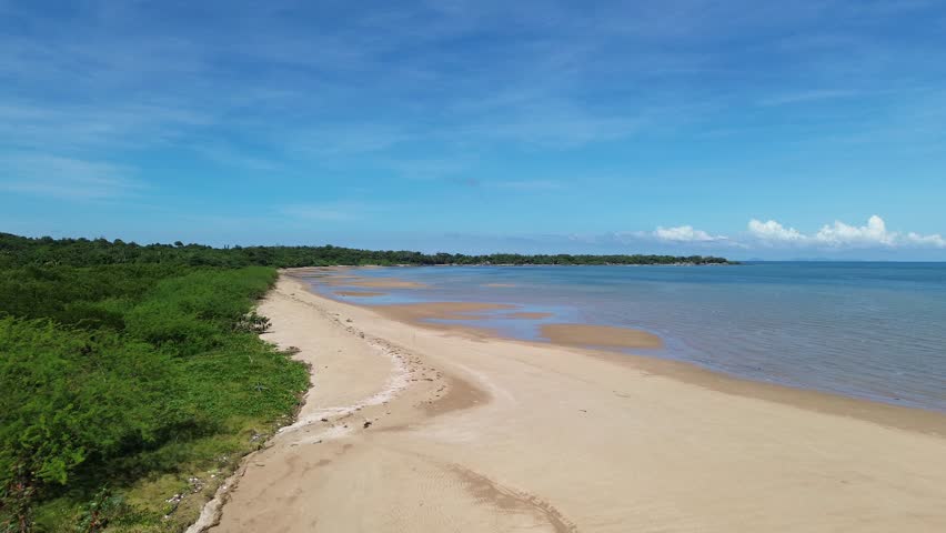 Drone footage showing a river flowing into the sea with a sandy sandbank at low tide, under clear sunny skies, highlighting natural coastal landscapes in Carles, Iloilo, Philippines.