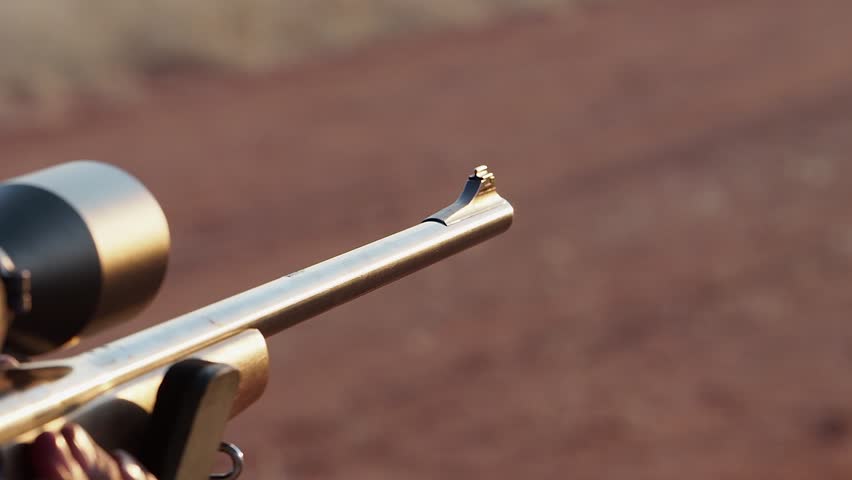 Rifle barrel with sighting scope kicks back when rifle is fired, closeup
