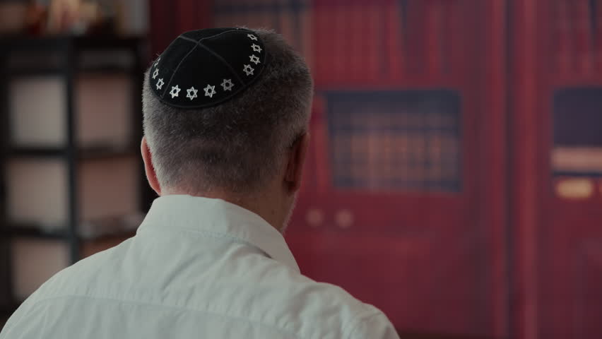 POV of Jewish Men from the back, covering a traditional Jewish Tallit blue and gold stripes and tassels. Praying