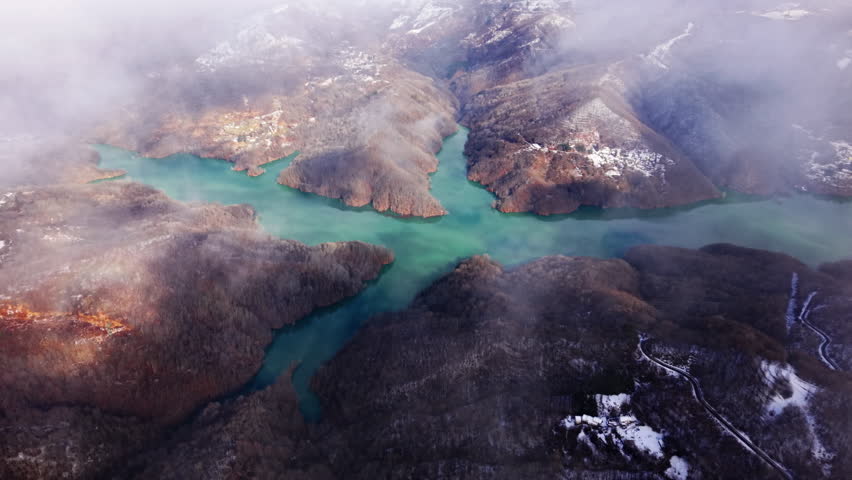 Aerial view of serene mountain lake with misty clouds in winter