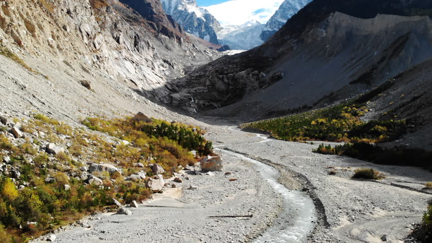 Barren Valley With Streams And Glaciers. Alpine Terrain Featuring Braided Streams And Distant Peaks. Media