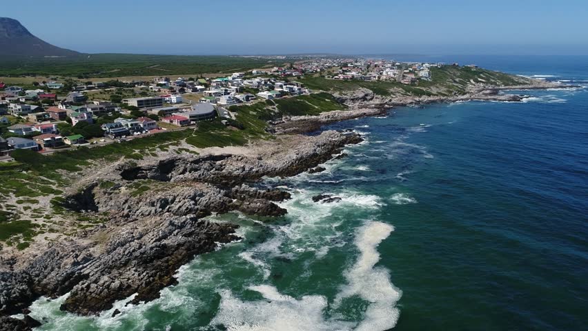 Aerial descends to rugged ocean coastline at De Kelders, South Africa