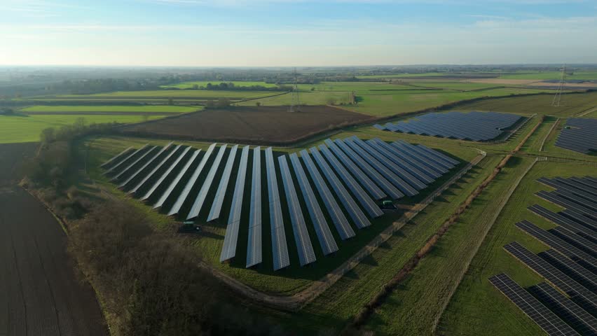 High altitude perspective of a large scale photovoltaic array in rural UK illustrating the green energy transition and sustainable infrastructure.