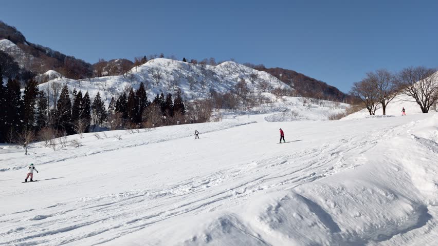 Wide winter landscape of a ski resort in Nagano, Japan with snowboarders riding