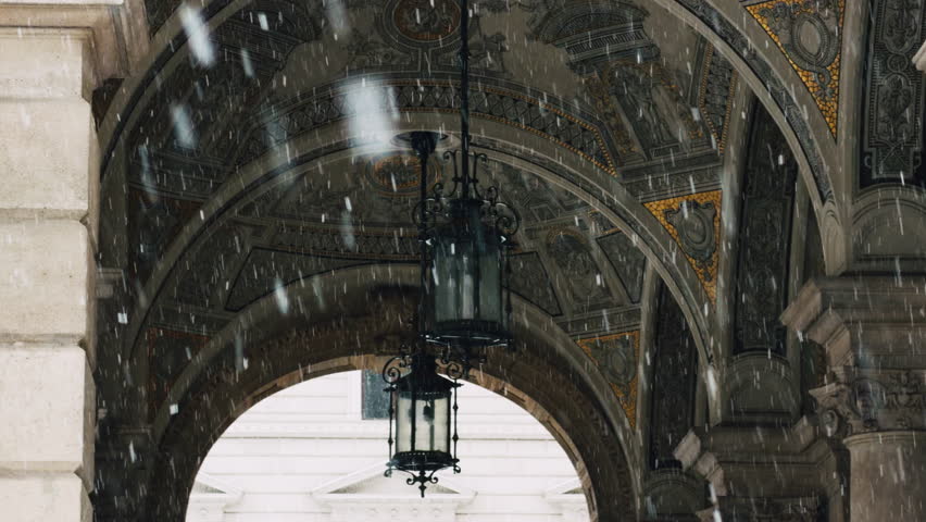 Detailed view of historic opera house architecture in Budapest during heavy snowfall. Ornate arches, classical design and cold seasonal atmosphere in Hungary.