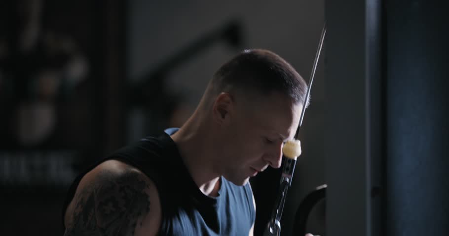 A man doing tricep exercise on training apparatus pumping his arms in the gym