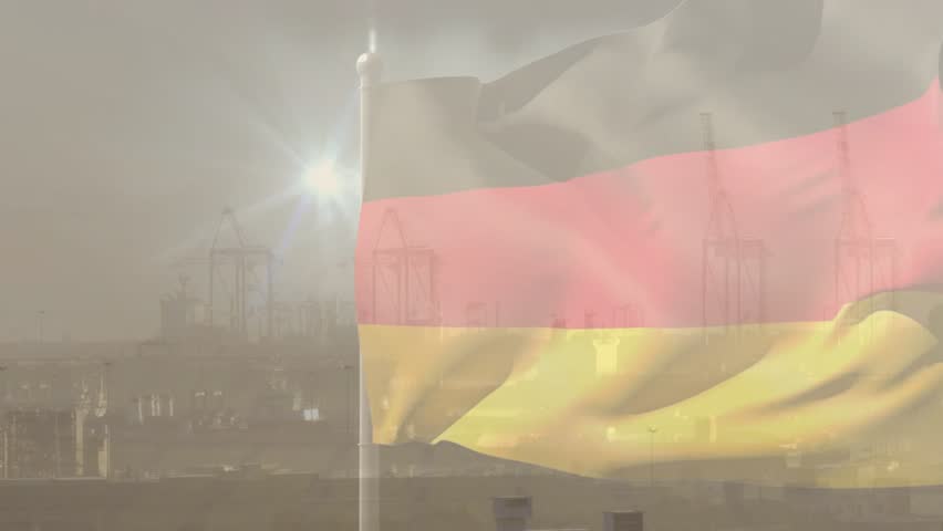 Flag responding to gusts, billowing, folding, rippling across and revealing hazy cranes behind. Ensign, wind, motion, harbor, industrial, backlit, misty