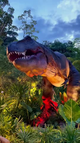 A dynamic dinosaur model in an outdoor park, captivating the audience as it moves its head and opens its mouth, adding a thrilling prehistoric element to the park