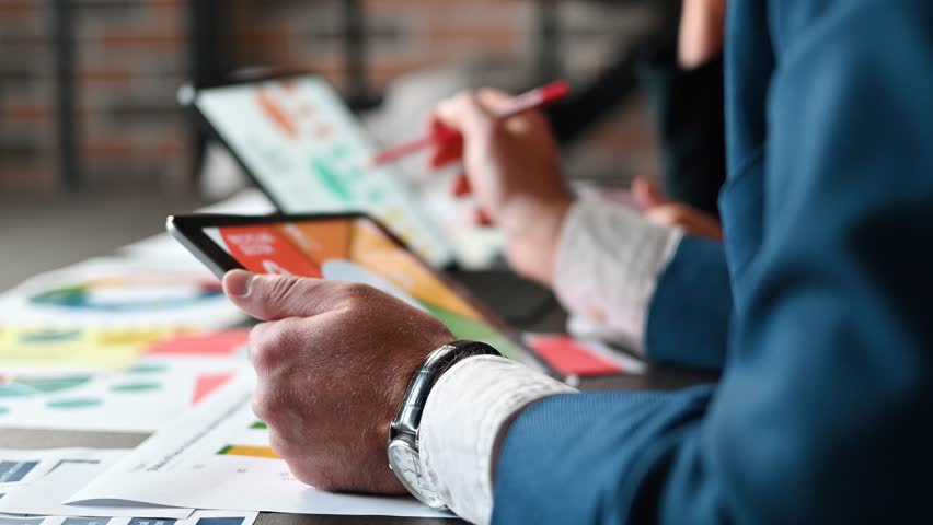 Business people analyzing financial growth and marketing strategy using digital tablets in office meeting