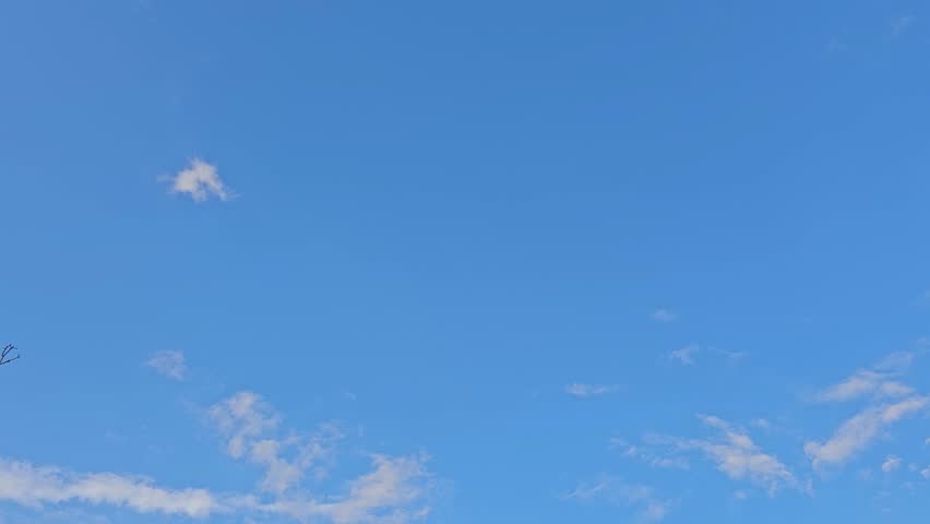 Camera moves through soft blue clouds in the sky descending toward earth over green field showing a fragment of rainbow after rain natural scenic landscape