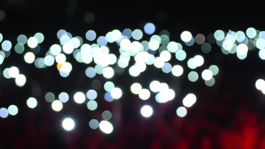 Blurred Crowd Holding Smartphone Lights at Night Concert
