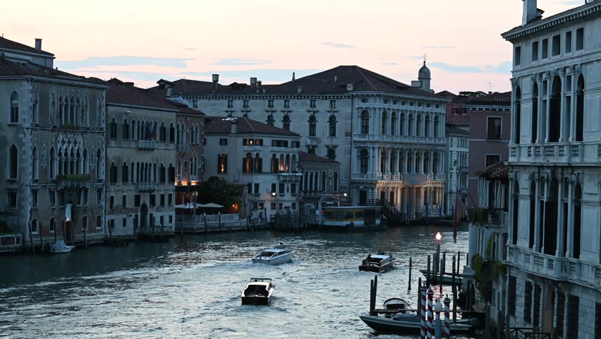 VENEZIA, ITALY - JULY 7th 2025: Grand Canal Sunset View with Historic Palaces. A classic and elegant view of the Grand Canal in Venice during a summer sunset. The footage captures the historic palaces lining the main waterway, the shimmering reflections on the water, and the unique atmosphere of the city at dusk