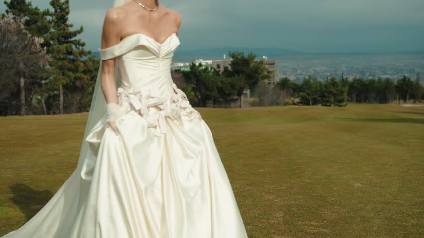 Joyful young bride enjoying the outdoor celebration on a meadow at sunset