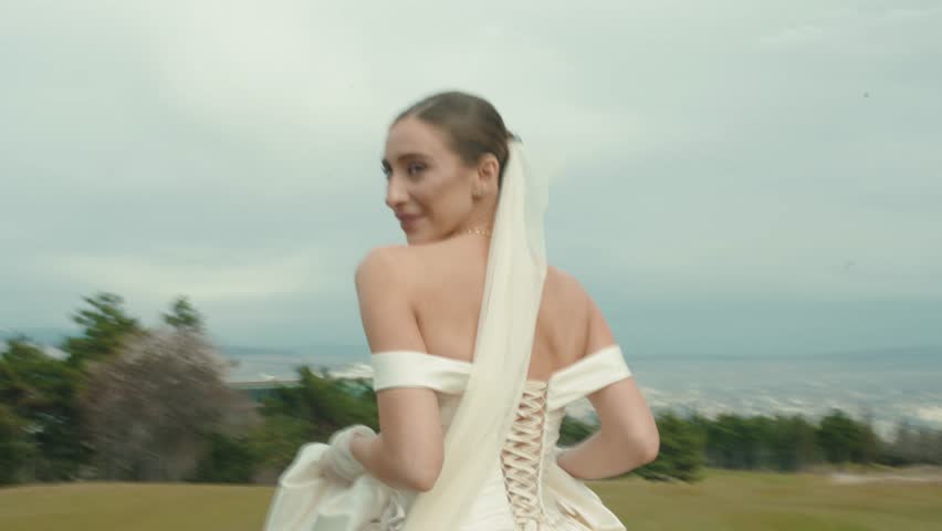 Joyful young bride enjoying the outdoor celebration on a meadow at sunset
