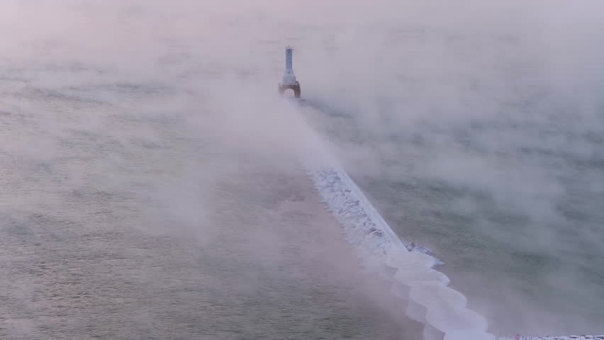 Telephoto drone shot around the Port Washington lighthouse, misty winter sunrise