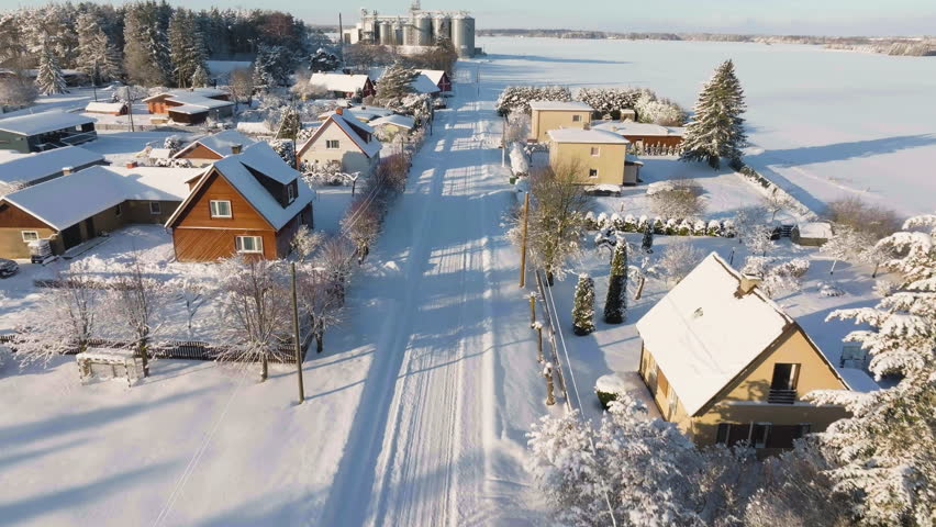 Aerial view flying along snowy streets and homes, sunny, winter day in Estonia