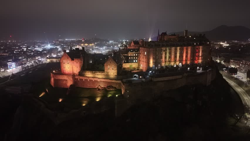 Aerial view of the Edinburgh Castle on Castle Rock at night with the illuminated city on the background Scotland, United Kingdom