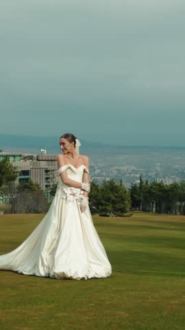 Joyful young bride enjoying the outdoor celebration on a meadow at sunset