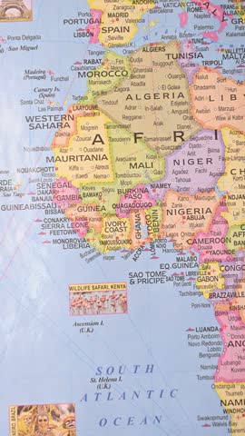 vertical top-view footage of male hand pointing to Freetown Sierra Leone on world map, West Africa geography concept