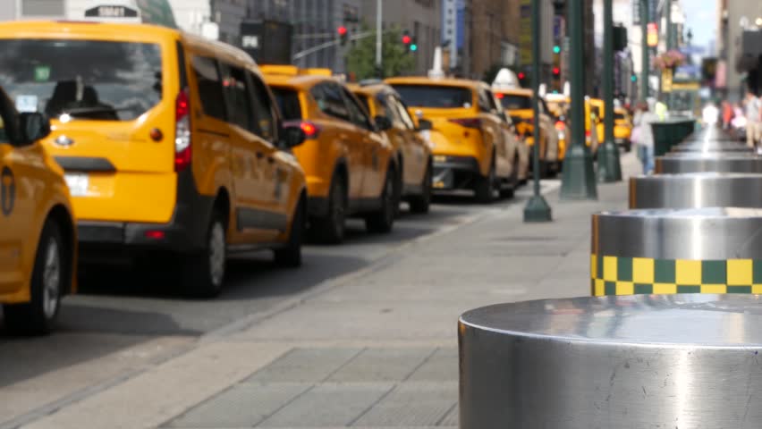 Manhattan Midtown street New York City, United States. Defocused row of yellow taxi cars. Many taxi cabs in line on 8th avenue near Penn Station. Taxi queue, urban road traffic, passenger transport.