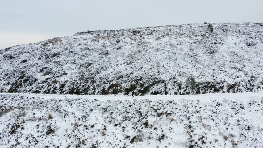 Aerial Side Perspective of People Walking Along a Snow Covered Hiking Trail, Wicklow Mountains