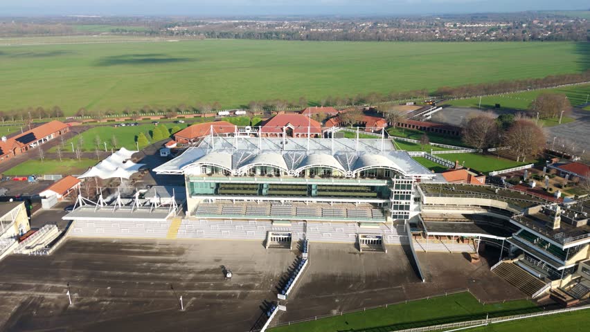 Aerial drone sequence of the grandstand and winning post at Newmarket Racecourse UK showcasing the heritage of the thoroughbred racing industry.