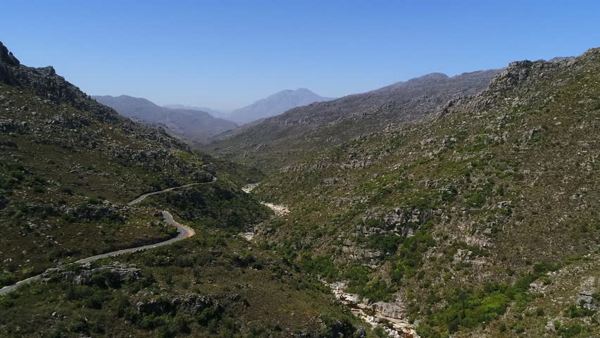 Serpentine road contours hillside in remote rugged rocky river canyon