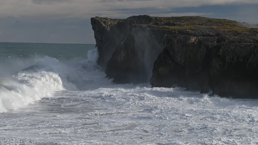 Powerful Storm Wild Waves on the Cantabrian Sea, Asturias Coast, Spain. Dramatic footage of a powerful Atlantic storm hitting the rugged coastline of northern Spain. Captured at the Pria Blowholes on the Asturias coast, this video showcases massive ocean swells crashing against the cliffs, with seawater forcefully shooting through natural blowholes in the rock.