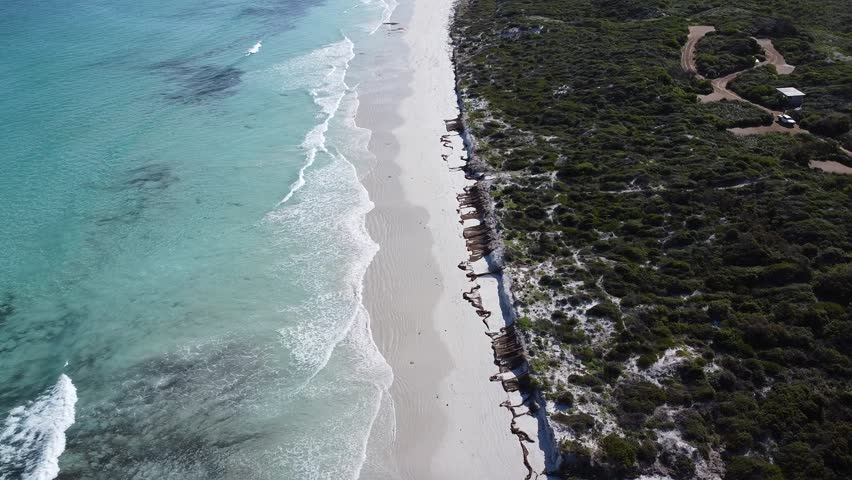 Forward moving drone shot over Cape Le Grand Beach in Western Australia, starting with a top-down view of turquoise ocean waves breaking on pristine white sand before gradually tilting up to reveal the full expansive coastline. Remote natural landscape inside Cape Le Grand National Park, showcasing untouched Australian shoreline, clear water, and rhythmic surf.