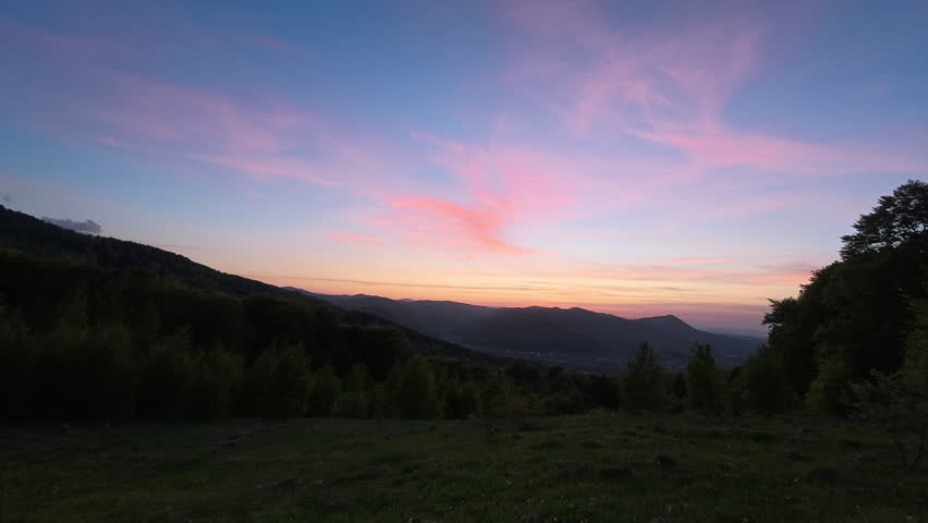 Majestic colorful cloudy sky over beautiful tops of hills in evening. Amazing warm sunset moment. Landscape scenery of warm dusk sunset in mountains at summertime