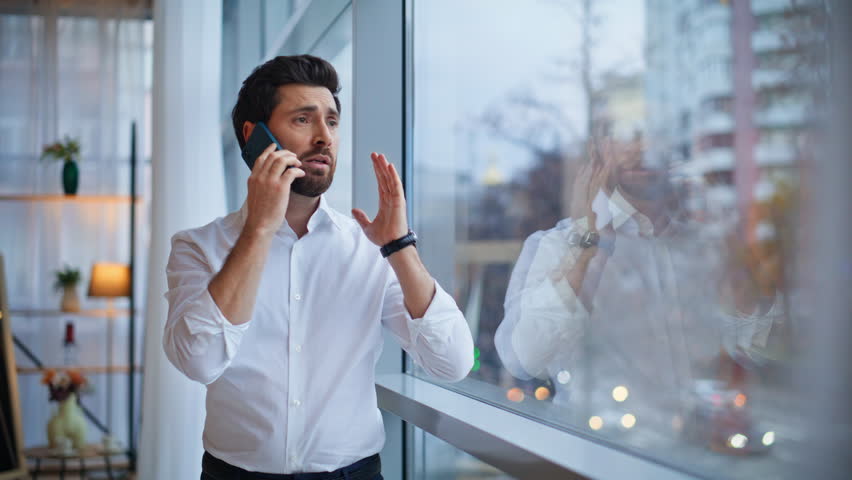 Calling entrepreneur discussing problem standing office hallway window closeup. Portrait worried businessman talking smartphone emotionally. Dissatisfied manager check time have annoyed conversation